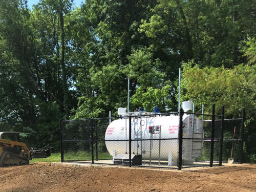 New white aboveground storage tank installed on a concrete pad inside a security fence