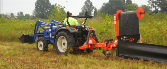 Operator installing silt fence with a tractor mounted plow along a field edge