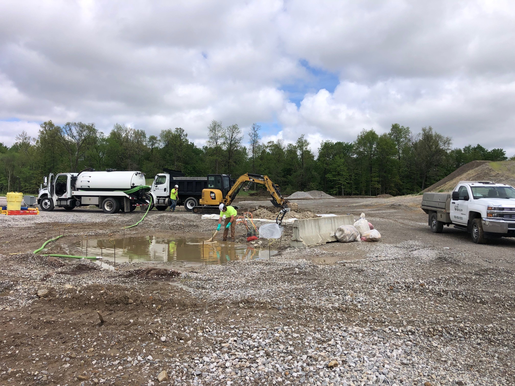 Crew member squeegeeing standing product into a vacuum hose at an open excavation